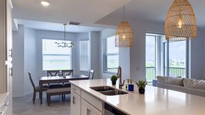 A modern kitchen with a central island, pendant lights, and a view of the outdoors. - Ave Maria - Relax & Golf. Golf resort with great amenities and gorgeous views. (Ave Maria)