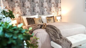 A bedroom with a bed, bedside tables, a bench, and patterned wallpaper. - Paderborn Oasis with Fireplace, Parking & Balcony, Stylish Home, 24/7 Check-in (Paderborn)