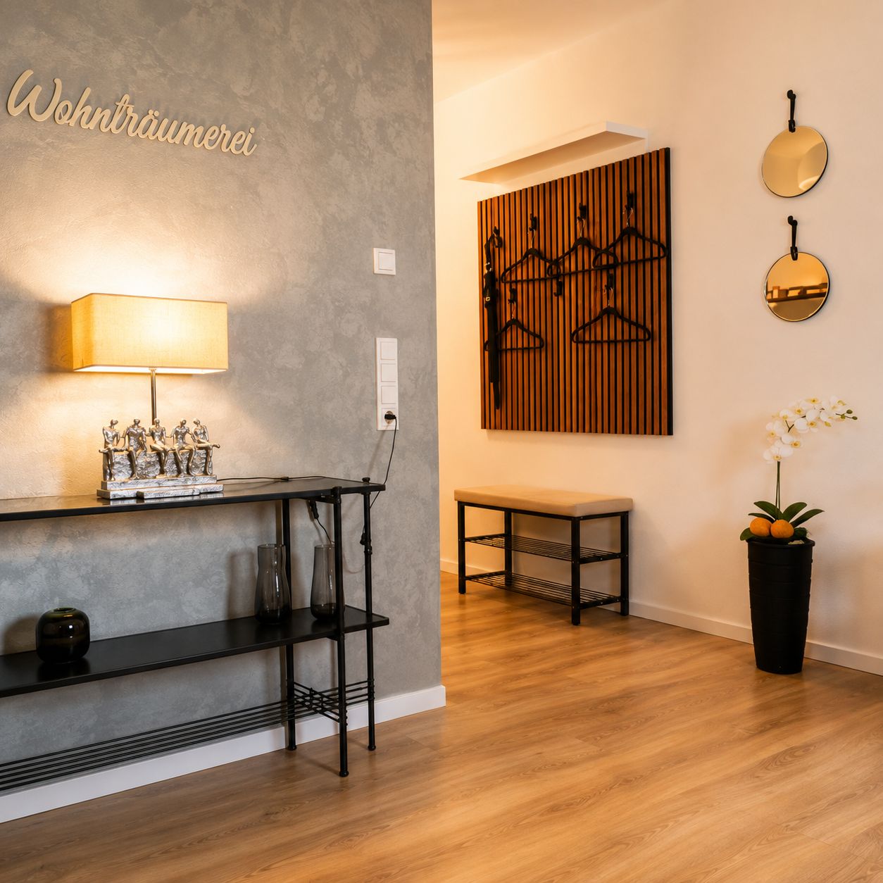 Ein modernes Interieur mit einer grauen Wand mit Struktur, einem schwarzen Metalttisch mit Lampe, Wandkunst aus Holzpaneelen, einer schwarzen Bank und einer Topf-Orchidee.