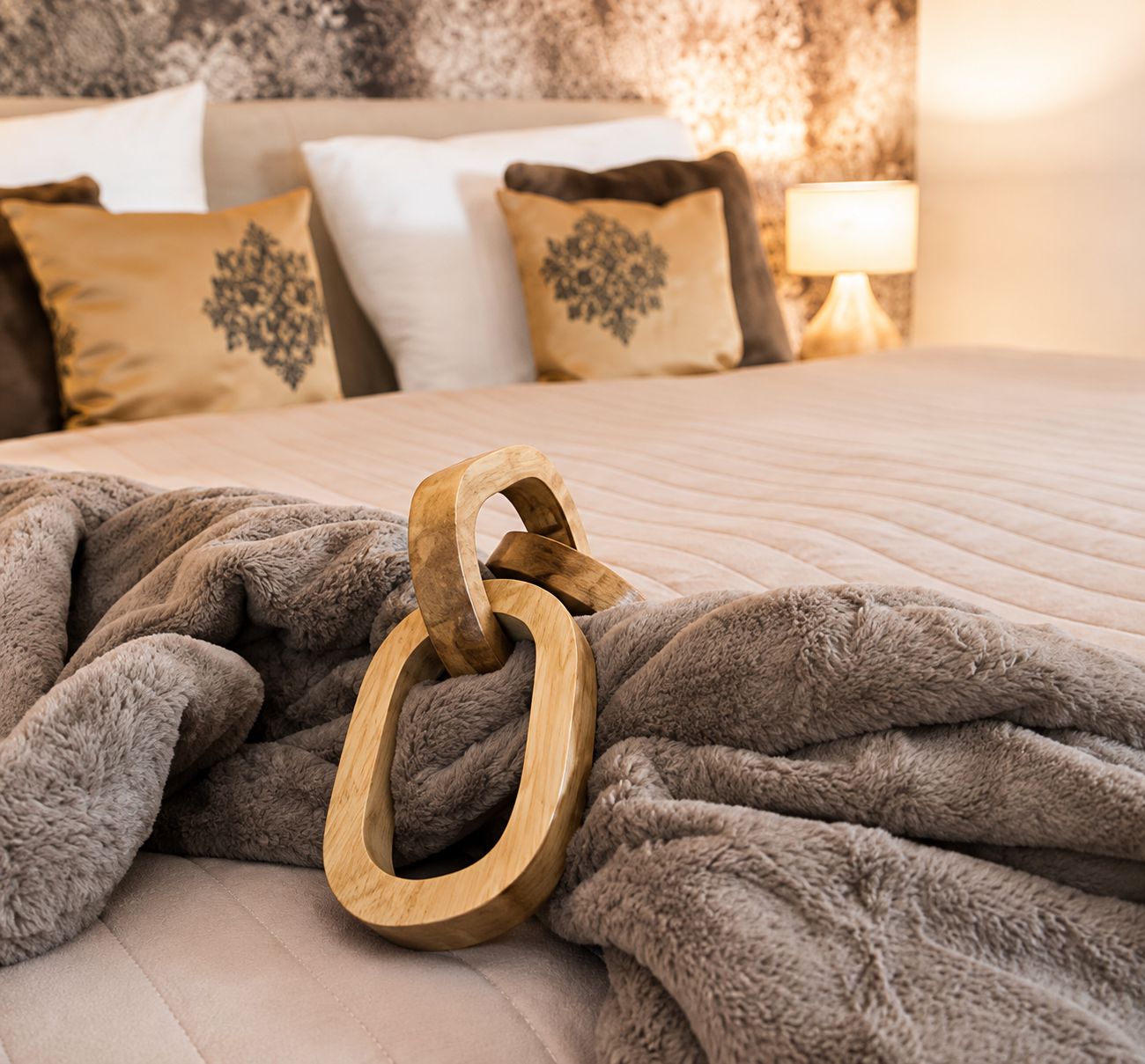 A bed with a grey blanket and a wooden shoe rack.