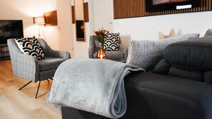 A modern living room with a grey sofa, a grey armchair, and a floor lamp. - Paderborn Oasis with Fireplace, Parking & Balcony, Stylish Home, 24/7 Check-in (Paderborn)