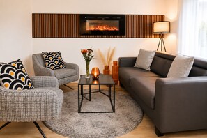 Un salon moderne avec une cheminée, deux canapés, une table basse et un lampadaire.