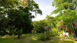 Un jardin luxuriant avec une balançoire et une chaise en plastique blanche.