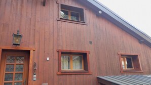Puinen rakennus, jossa on kolme ikkunaa ja ovi, jossa on koristeelliset lasipaneelit.