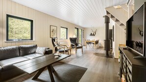 Ein modernes Wohnzimmer mit einer Couch, Sesseln, einem Esstisch und einem Kamin.