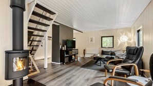 Ein modernes Wohnzimmer mit Kaminofen, einer schwarzen Ledersofa und einer Treppe, die in eine weitere Ebene führt.