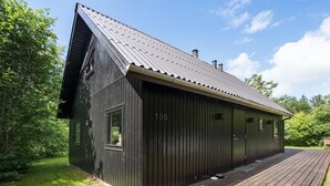 Ein schwarzes Holzgebäude mit geneigtem Dach, Nummer 135, mit einer Holzdachterrasse und mehreren Fenstern.