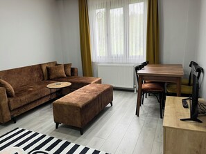 Apartamento superior, 1 cama Queen e sofá-cama, para não fumantes, vista para a cidade | Área de estar | Smart TV 84 cm com canais a cabo