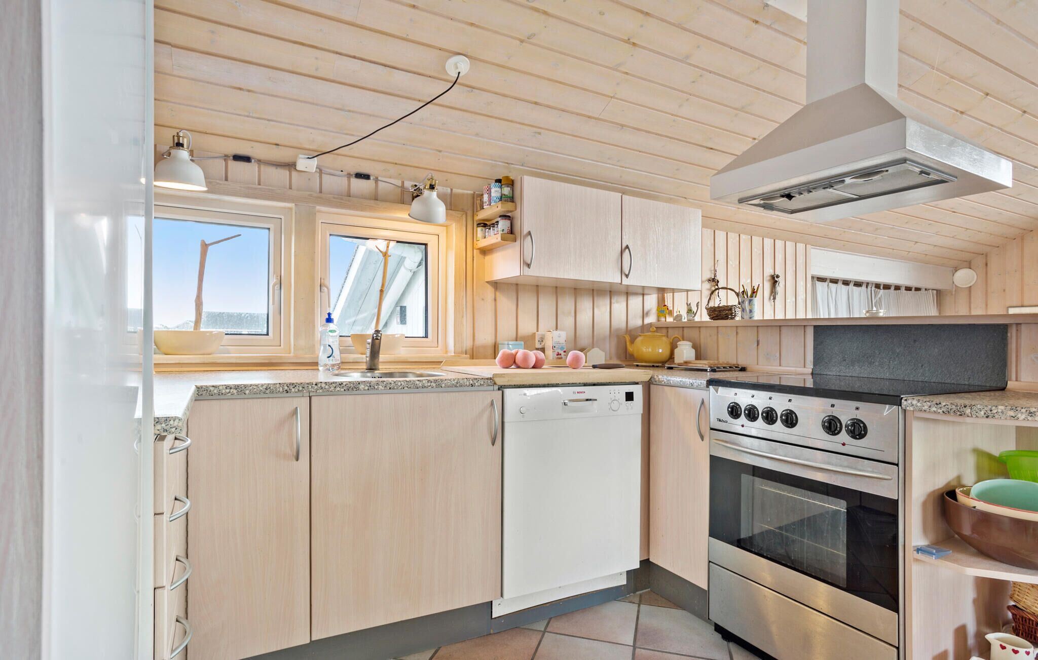 A modern kitchen with wooden cabinets, a built-in oven, and a window overlooking a scenic view.