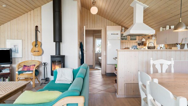 A cozy living room with a fireplace, a dining area, and a kitchen. - Nice home in Frøstrup with sauna (Frøstrup)