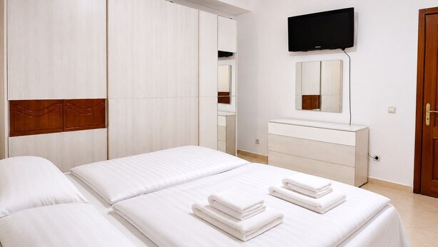 A hotel room with two beds, a TV, a mirror, and a wooden wardrobe. - Saranda 55 (Sarandë)