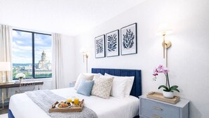 Ein modernes Hotelzimmer mit einem großen Bett, einem Schreibtisch und Blick auf die Stadt.