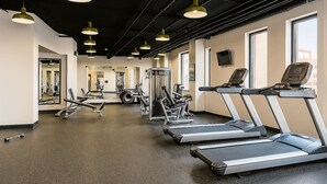 Une salle de sport équipée de tapis de course, d’appareils de musculation et d’un mur recouvert de miroirs.