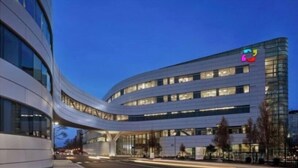 Un hôtel moderne à la façade incurvée, doté de plusieurs étages et arborant un logo bien visible en haut à droite.