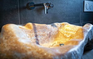 Ein Waschbecken aus Stein mit einem modernen Wasserhahn in einem Badezimmer.