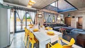 A modern dining area with a long table, yellow chairs, and a stone wall backdrop. - Amazing home in Kanfanar (Kanfanar)