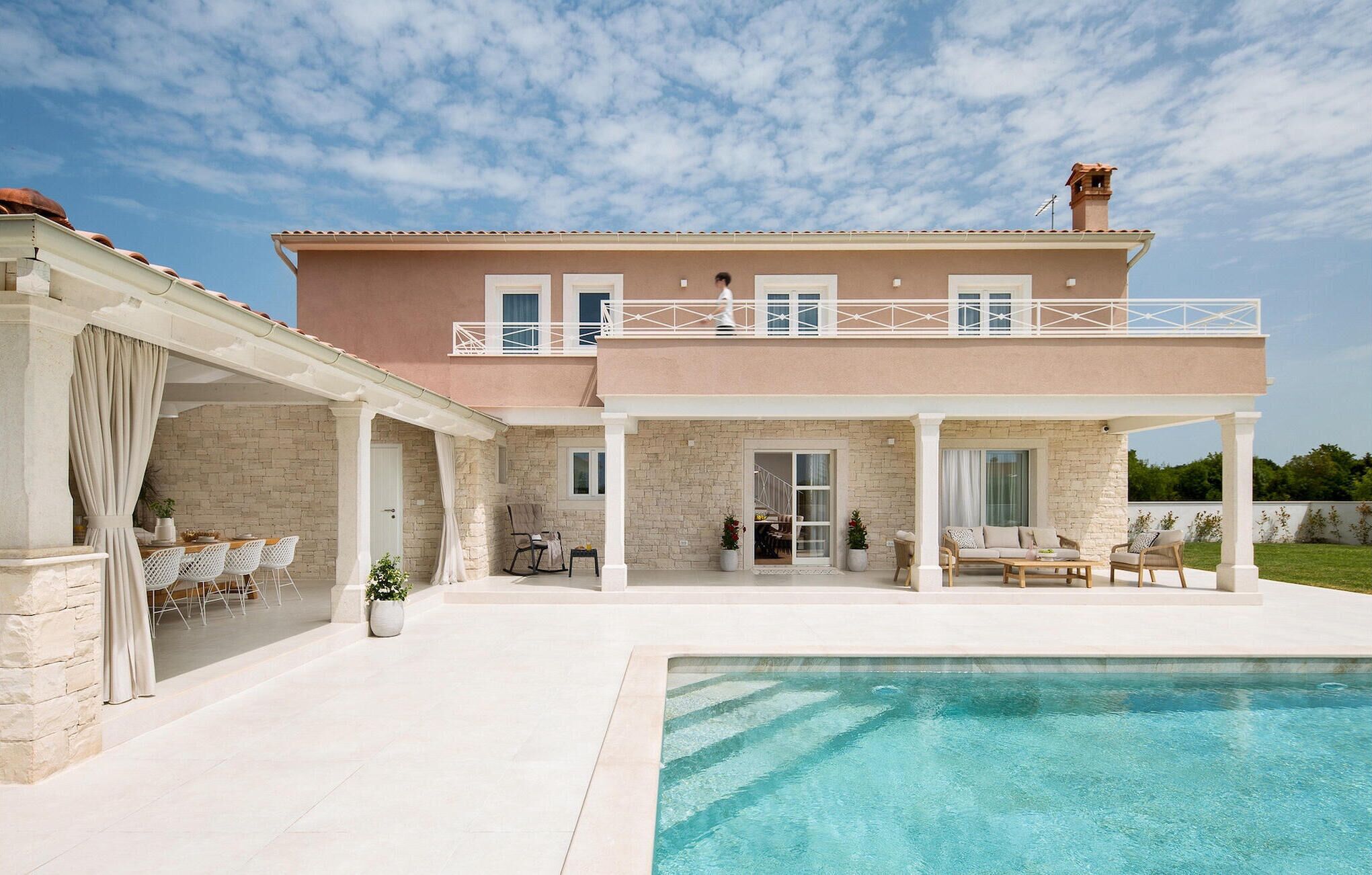 A two-story house with a pool, outdoor seating, and a covered patio area.