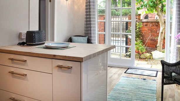 Eine moderne Küche mit Einbauherd, Kaffeemaschine und Blick auf einen Garten durch eine Glastür.