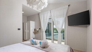 A modern hotel room with a bed, a TV, a wardrobe, and a balcony with a view. - Gorgeous home in Garica (Garica)