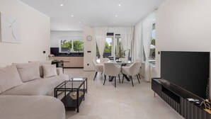 A modern living room with a sofa, coffee table, TV, and dining area with chairs and a table. - Gorgeous home in Garica (Garica)