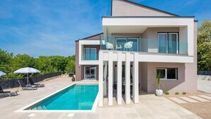 A modern two-story house with a swimming pool, large windows, and a balcony with outdoor furniture. - Gorgeous home in Garica (Garica)