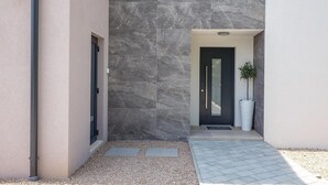 A modern building entrance with a dark door, a security camera, and a potted plant. - Gorgeous home in Garica (Garica)