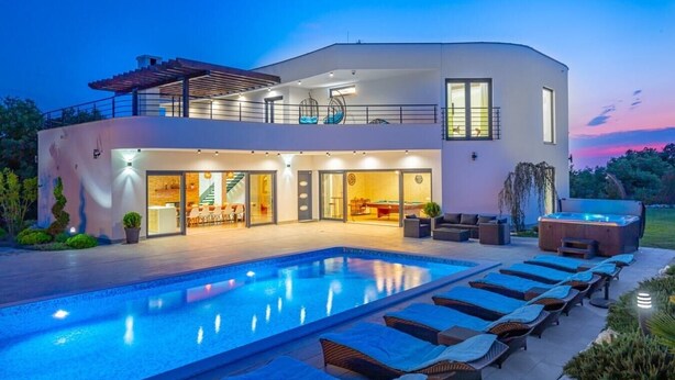 Una casa moderna de dos pisos con piscina, mobiliario exterior y jacuzzi.