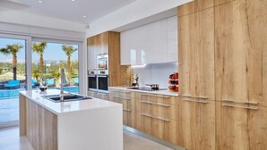 Una cocina moderna con una isla central, armarios de madera y vista a una piscina.