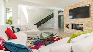 Una sala de estar moderna con un sofá blanco, una mesa de centro de vidrio y una chimenea.