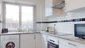 Une cuisine moderne équipée d’un lave-linge, d’un four et d’une grande fenêtre.