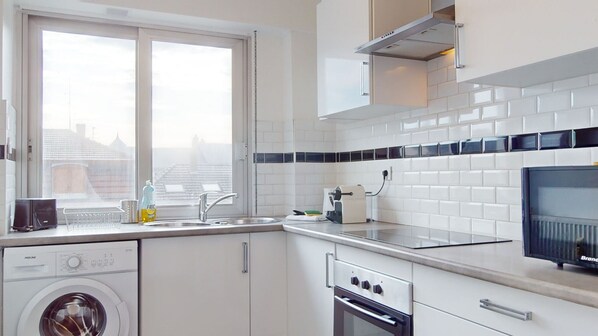 A modern kitchen with a washing machine, oven, and a large window.
