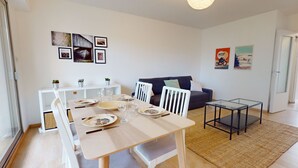 Un salon moderne avec une table à manger pour quatre personnes, un canapé et une petite table basse.