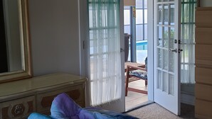 Una camera da letto con un letto, una cassettiera e una porta che dà su un balcone.
