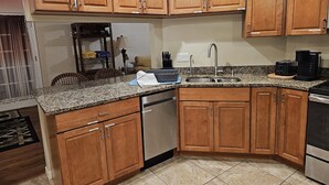 Cucina con mobili in legno, piani in granito, elettrodomestici in acciaio inossidabile e lavastoviglie integrata.