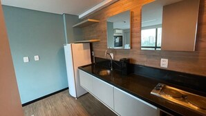 A modern kitchen with a built-in oven, a sink, and a large mirror above the countertop. - Flat Aconchegante em Boa Viagem (Recife)