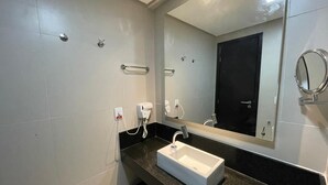 A bathroom with a white sink, a mirror, and a hairdryer. - Flat Aconchegante em Boa Viagem (Recife)