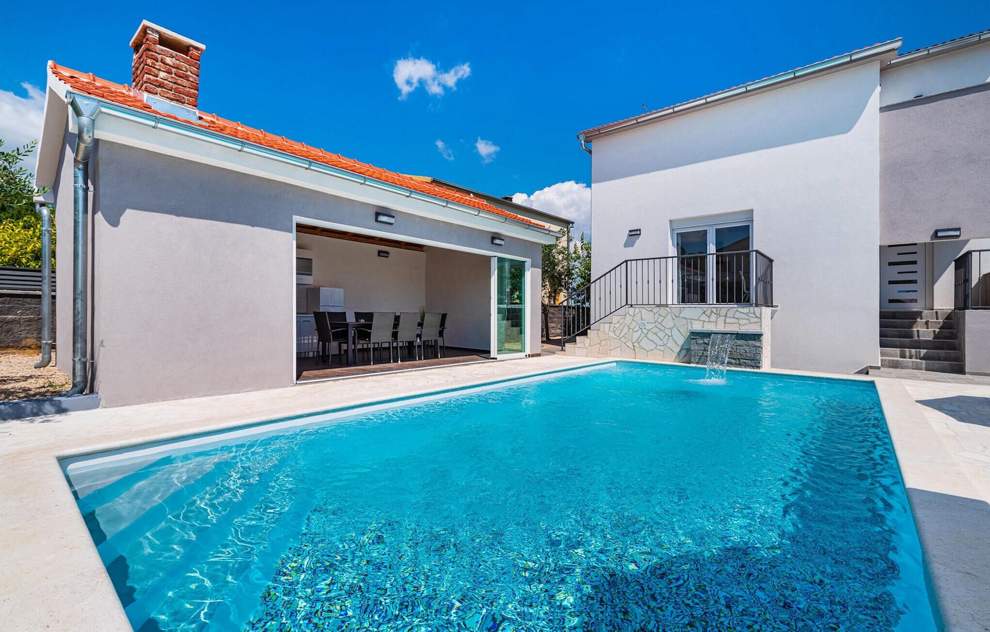 A modern house with a swimming pool, a covered patio, and a stone staircase.