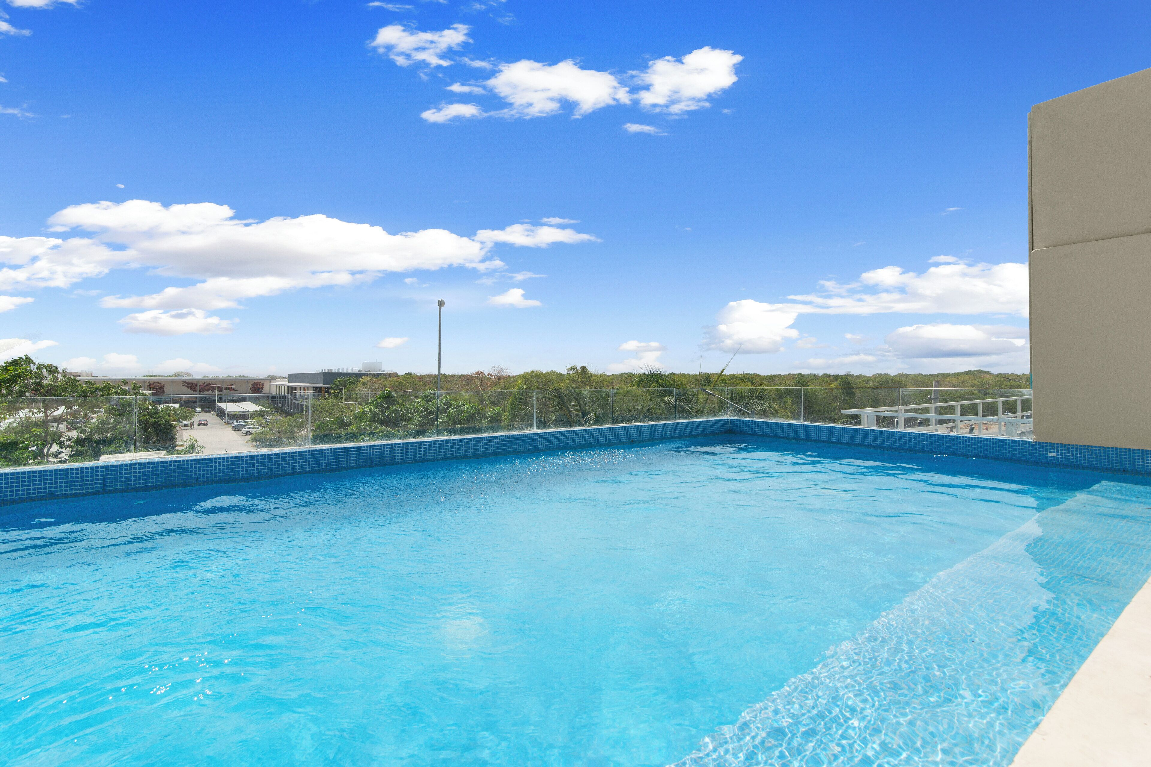 A clear blue swimming pool with a view of the sky and distant buildings.