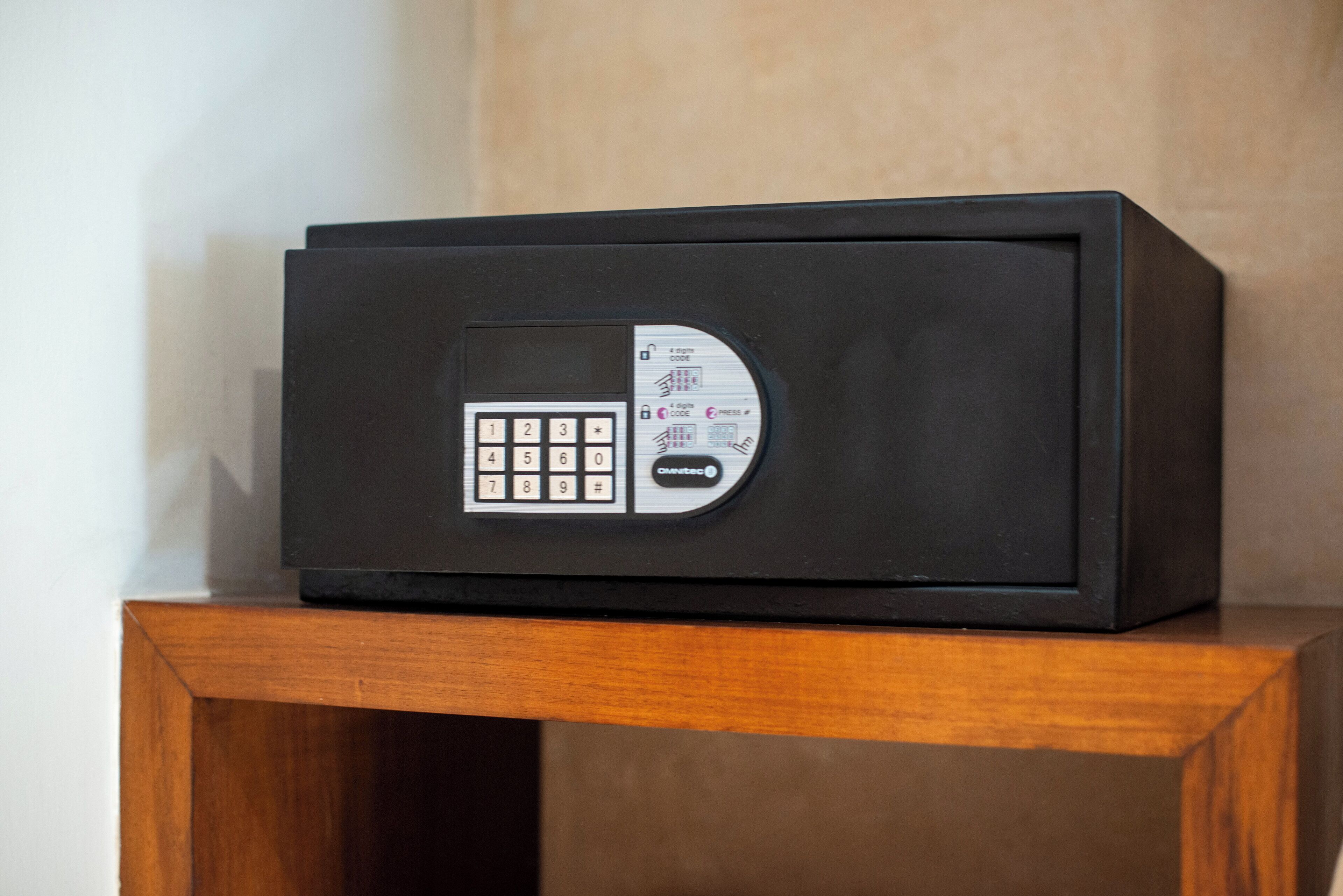Um cofre preto com teclado num pedestal de madeira.
