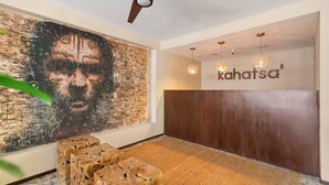 Una habitación con un mural grande, un ventilador de techo, un panel de pared de madera y un letrero que dice "kahatsa".