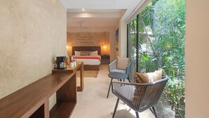 Un dormitorio con cama, mesita de noche y una silla. Se ve un ventanal con vistas al entorno natural.