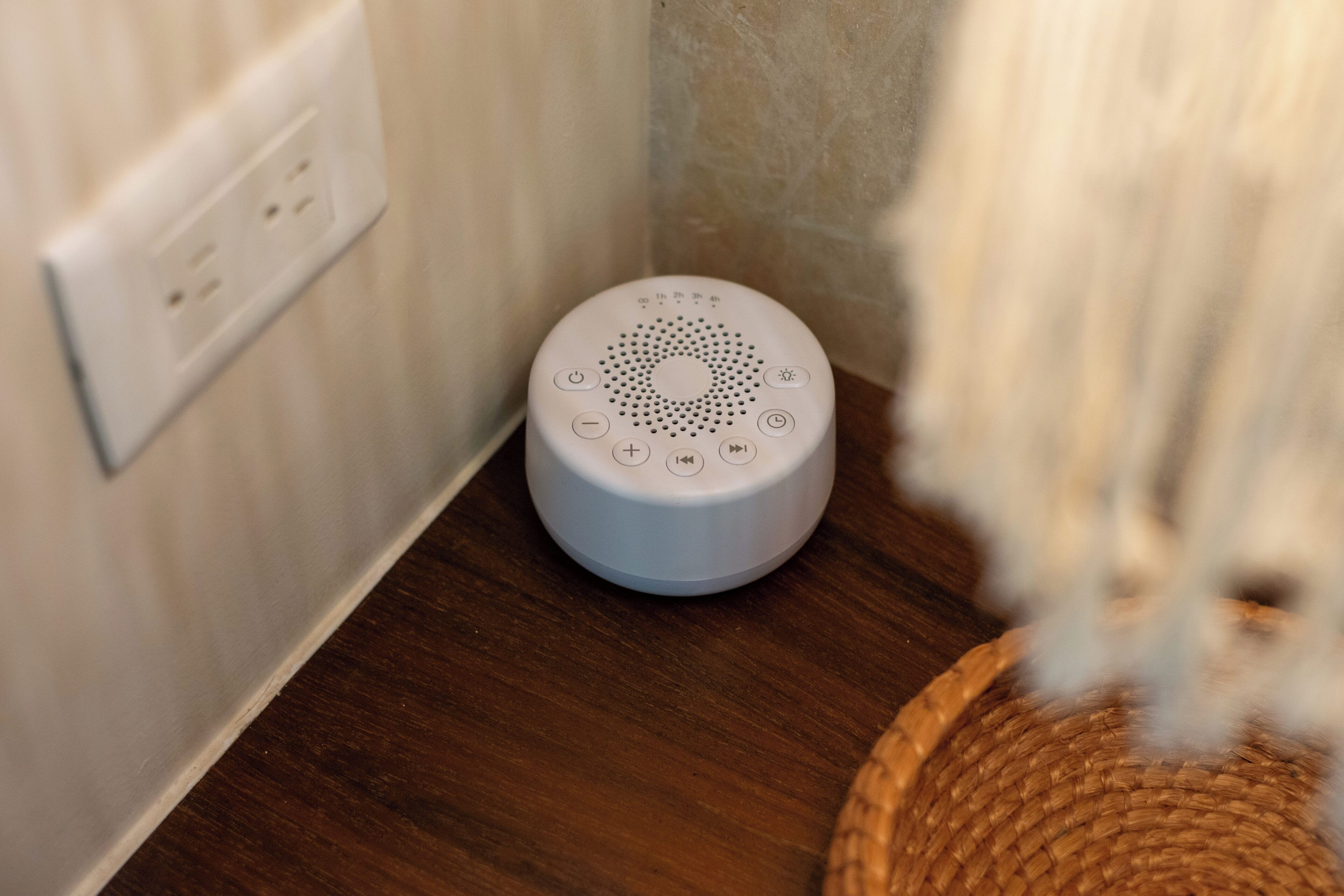 A white device on a wooden floor near a wall socket.
