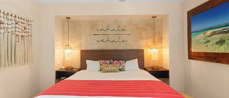 A bedroom with a bed, a ceiling fan, a wall with a motivational quote, and a framed picture on the wall.