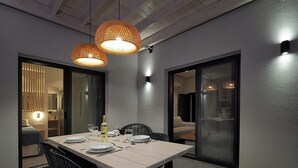 A dining area with a table set for four, two pendant lights, and a sliding glass door leading to a living area.