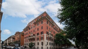 A multi-story building with a red facade, a crosswalk, and tram tracks. - Top view luxury apartment Piazza del Popolo (Roma)