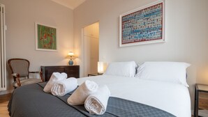 A hotel room with a bed, two chairs, a dresser, a lamp, and artwork on the walls. - Top view luxury apartment Piazza del Popolo (Roma)