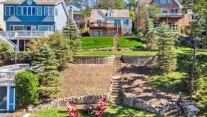 A residential area with houses, a small dock, and a stone retaining wall. - The Cozy Lake House  (Wonder Lake)