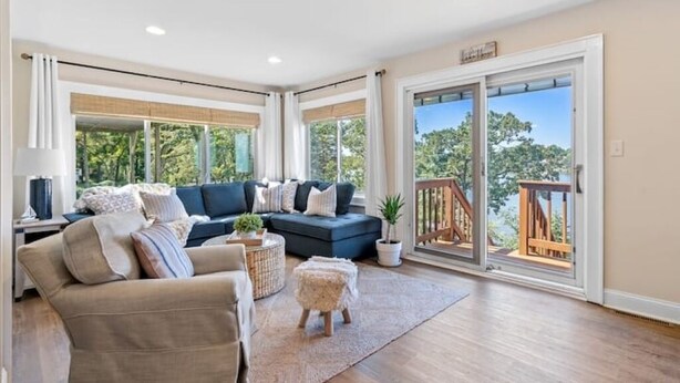 A spacious living room with a sofa, a coffee table, and a rug. There is a sliding glass door leading to an outdoor deck. - The Cozy Lake House  (Wonder Lake)