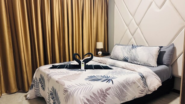 Habitació d'hotel amb llit, cortines, una petita taula de nit i una làmpada.