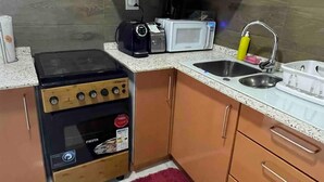 Una cuina compacta amb armaris de fusta, forns de gas, microones i un rentaplat.